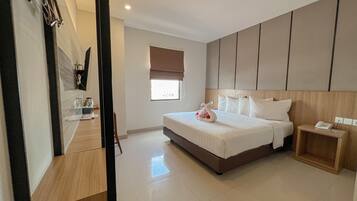 A hotel room with a large bed, bedside tables, a window with blinds, and a wooden headboard.