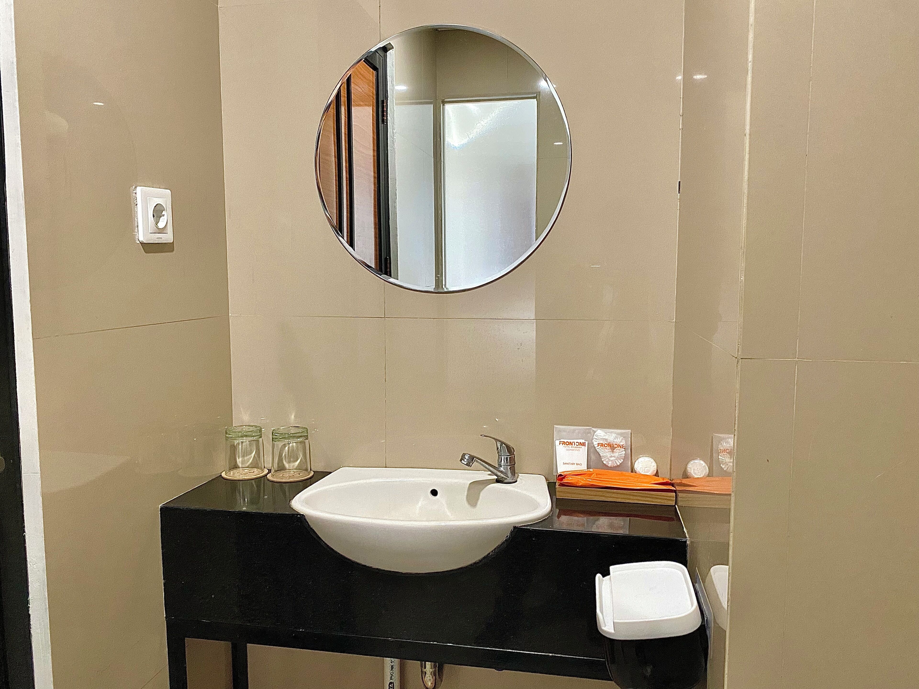 Een badkamer met een wit wastafelmeubel, een ronde spiegel en een zwart aanrecht.