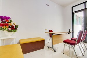 A reception area with a desk, chairs, a bench, and a flower arrangement. - OYO 90322 Joy Homestay Near Bella Terra Lifestyle Center (Jakarta)