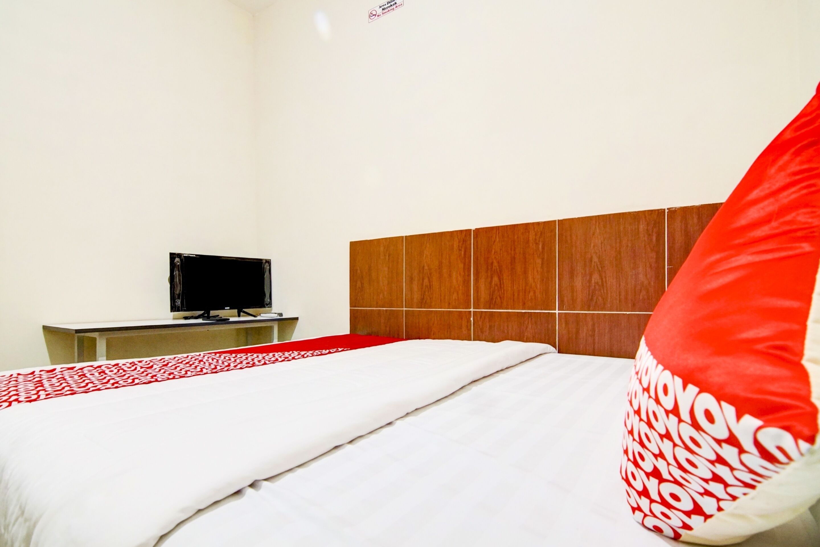 Een hotelkamer met een bed, een televisie op een standaard en een houten hoofdbord.