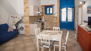 Un espacio habitable compacto con comedor, kitchenette y una puerta azul.