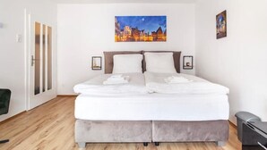 A modern hotel room with a large bed, a cityscape painting above it, and a view of the city at night. - City Apartment in Berühmter Lage (Hildesheim)