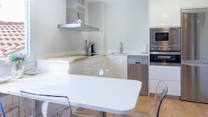 A modern kitchen with white cabinetry, stainless steel appliances, and a large window providing natural light. - Bright apartment in Mundaka, perfect for couples and families, near the beach (Mundaca)