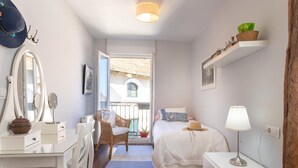 A bedroom with a bed, bedside table, lamp, dresser, chair, and a view of the outside. - Bright apartment in Mundaka, perfect for couples and families, near the beach (Mundaca)