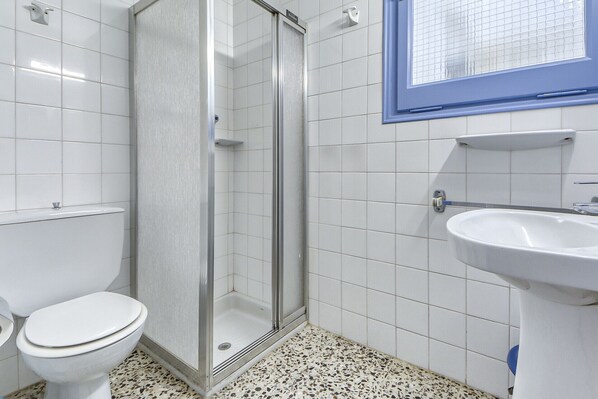 A bathroom with a shower, toilet, and sink.