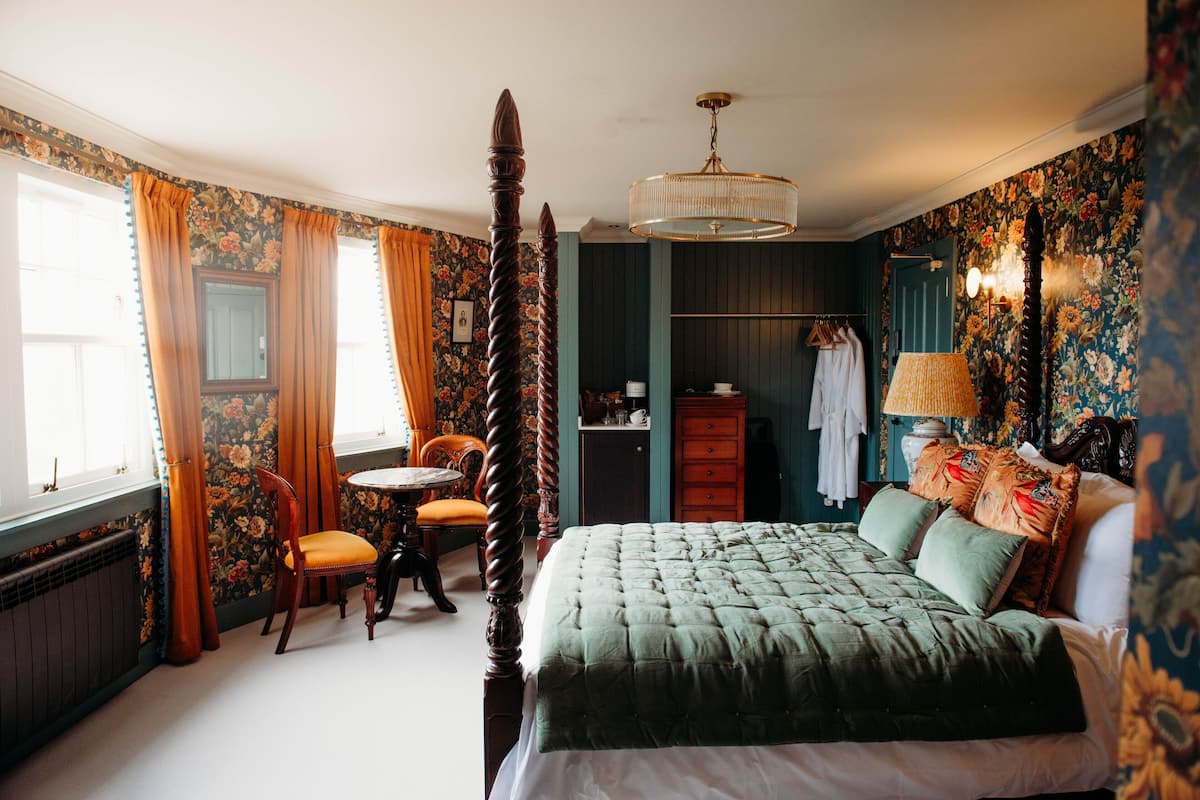 A bedroom with a four-poster bed, a round table, and a chair.