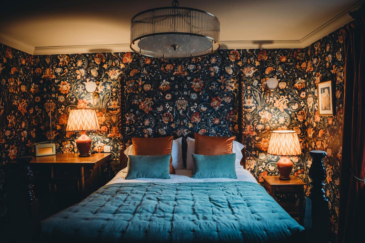A bedroom with a large bed, two nightstands, and a chandelier.