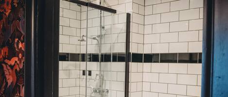 Een moderne badkamer met een douchekabinet van glas, witte betegelde wanden, een toilet en een wastafel.