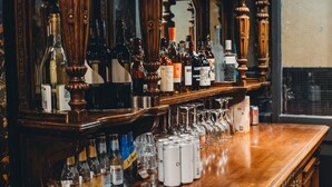 Un espace bar avec des meubles en bois, des bouteilles, des verres et un miroir.