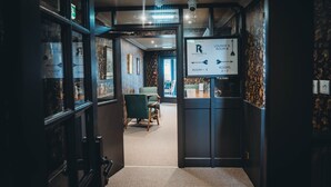 Un hall d’hôtel comprenant un comptoir d’accueil, un panneau indiquant l’emplacement des chambres et un escalier menant aux étages supérieurs.