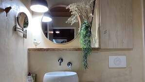 Un baño con un espejo redondo, un lavabo blanco y un tocador de madera.