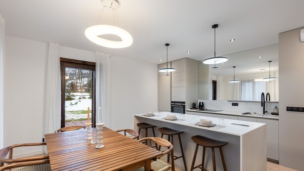 Una cocina moderna con una isla central, una mesa de comedor de madera y taburetes de bar.