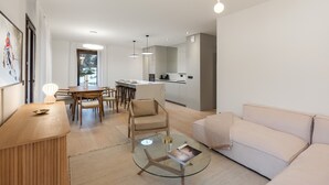 Una sala de estar moderna con una mesa de centro de vidrio, un sofá color beige y un comedor con sillas de madera.
