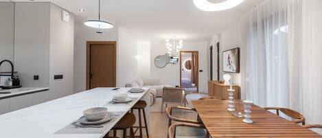 Una cocina moderna con una isla grande, una mesa de comedor de madera e iluminación colgante.