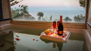 A bathtub with a tray holding a bottle, glasses, candles, and rose petals. - Dream villa in San Felice Circeo (Faro)
