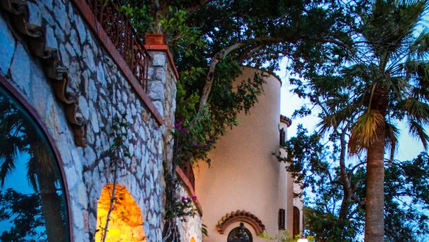 A stone pathway leading to a building with a dark door and a light fixture. - Dream villa in San Felice Circeo (Faro)
