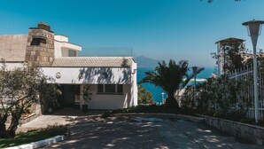 A modern building with a stone facade, a tiled roof, and a view of the sea. - Villa Sacco - Sorrento Coast (Priora)