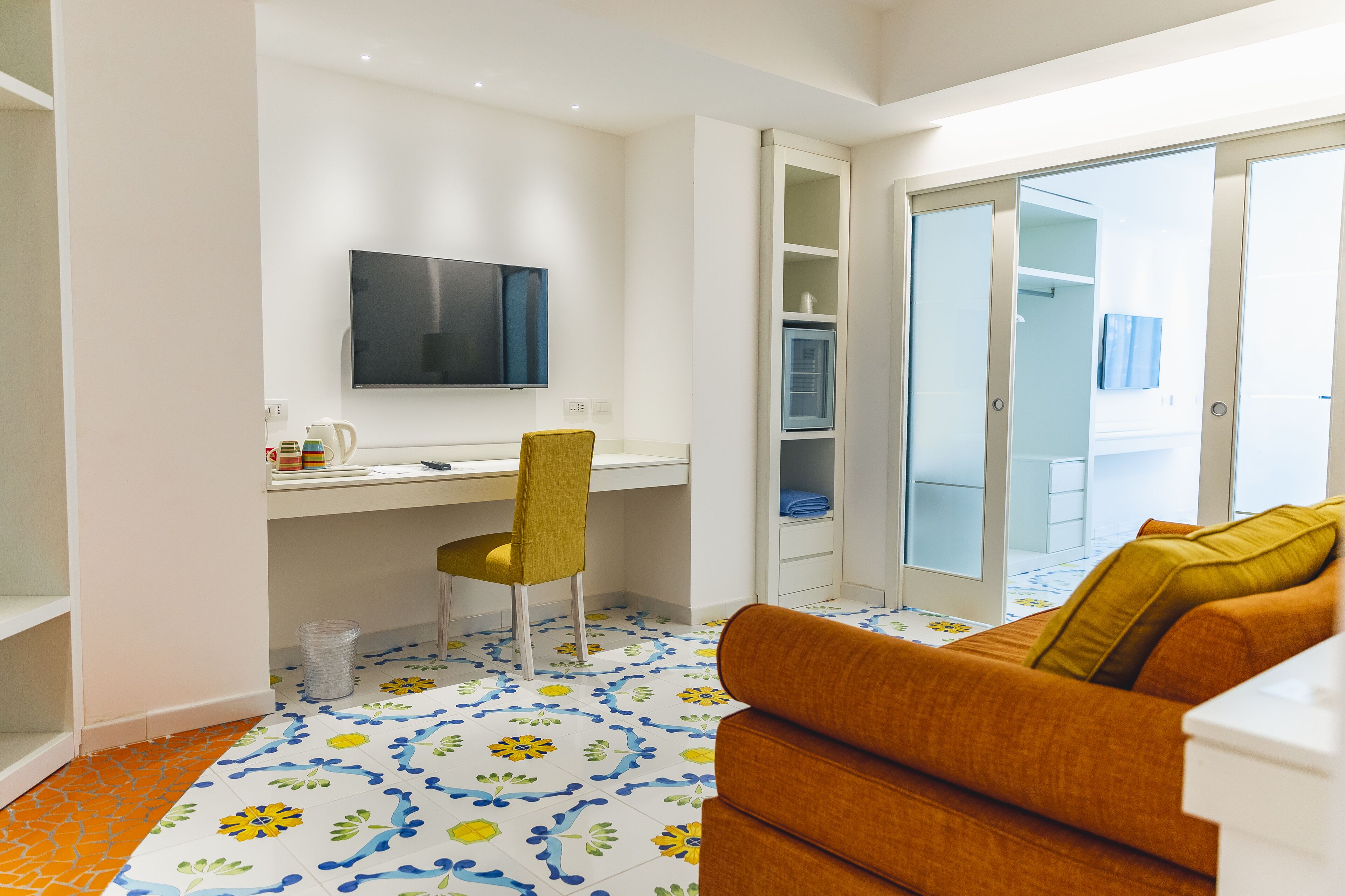 A modern room with a desk, chair, and orange sofa.
