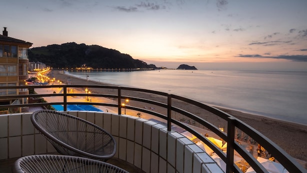 A balcony with wicker chairs overlooking a beach at sunset. - Charming 3-bedroom apartment in Zarautz, close to the beach (Zarauz)