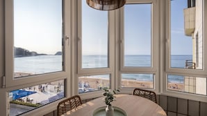 A dining area with a large table, multiple windows offering ocean views, and wicker chairs. - Charming 3-bedroom apartment in Zarautz, close to the beach (Zarauz)