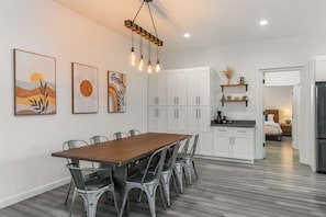 Een moderne keuken met witte kasten, een eettafel met stoelen en kunstwerken aan de muur.