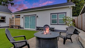 A patio with a round fire pit, two chairs, and a table.
