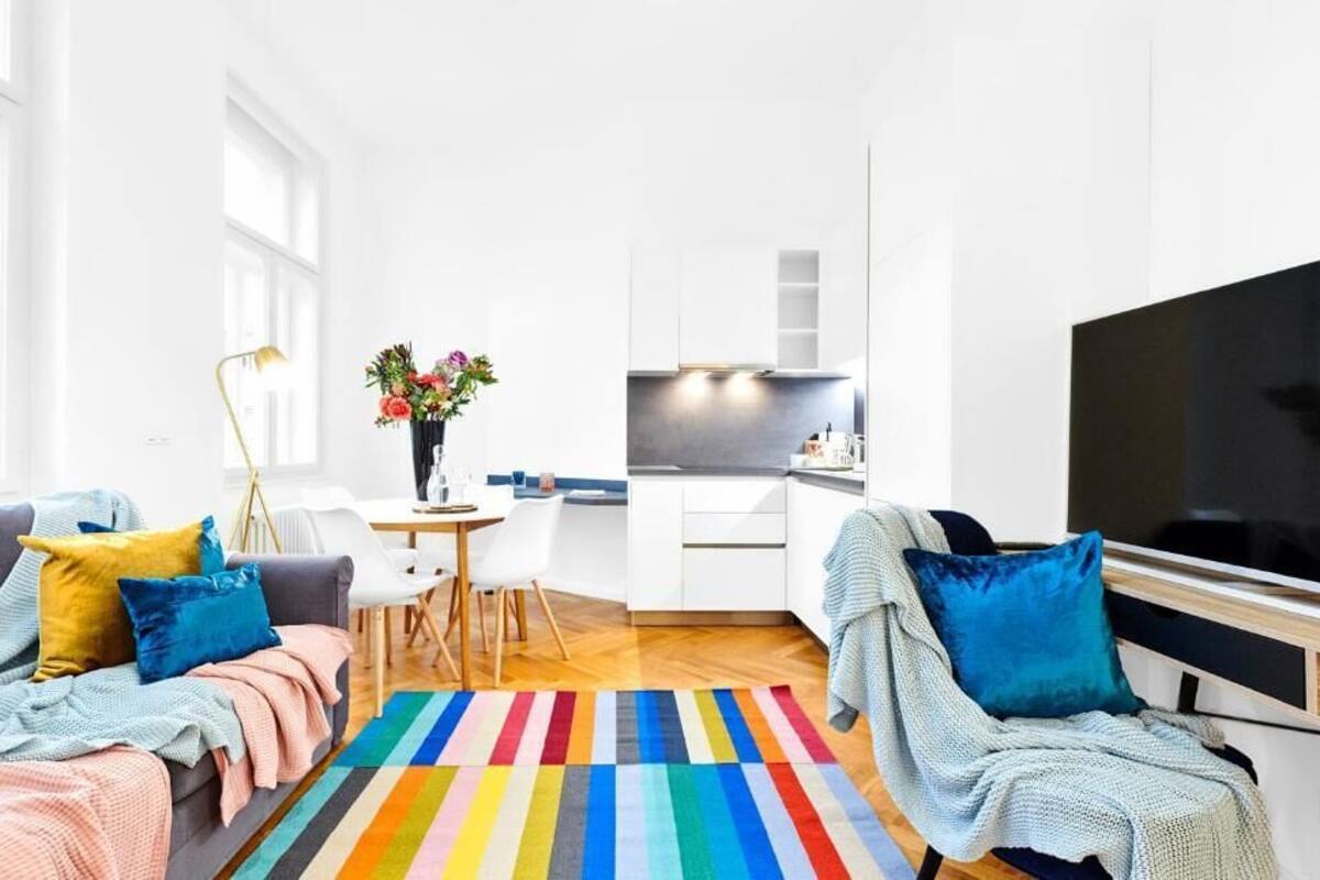 Un salon moderne avec un canapé, un téléviseur et un tapis rayé aux couleurs vives.