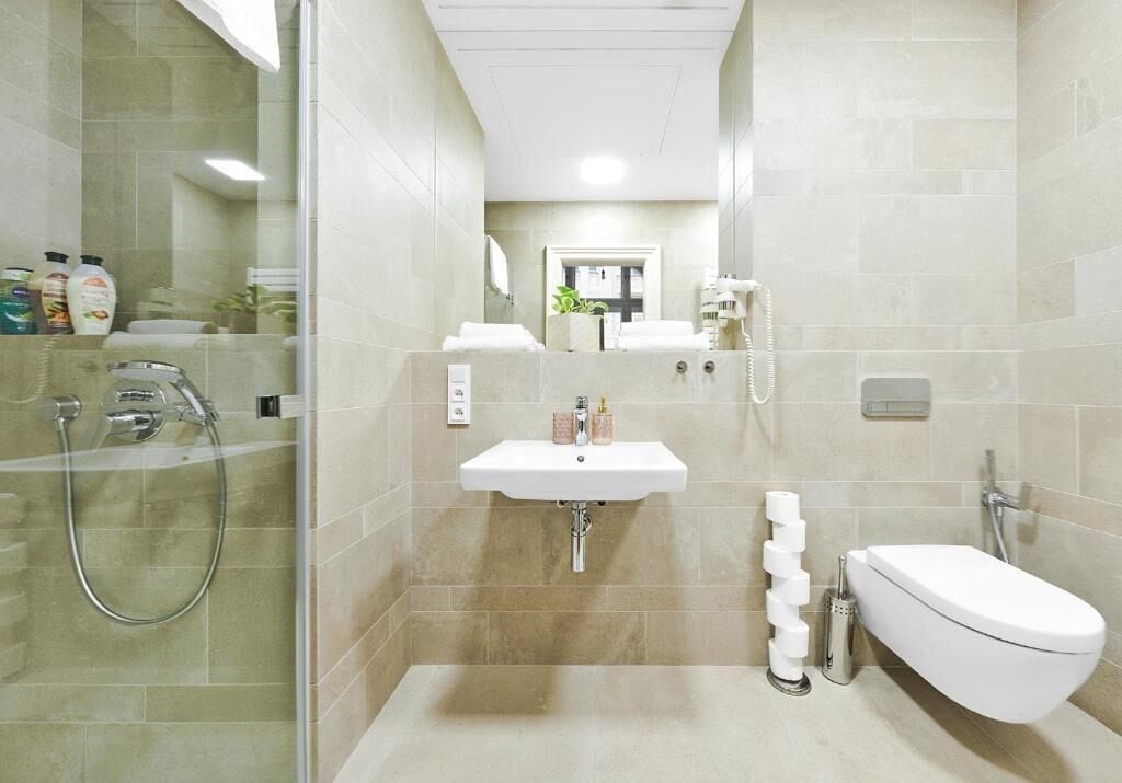 A modern bathroom with a glass-enclosed shower, a white sink, and a toilet.