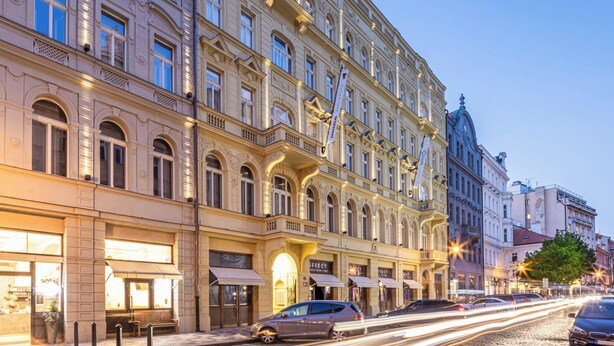 En historisk byggnad med utsmyckad arkitektur, stora fönster och en kullerstensgata.