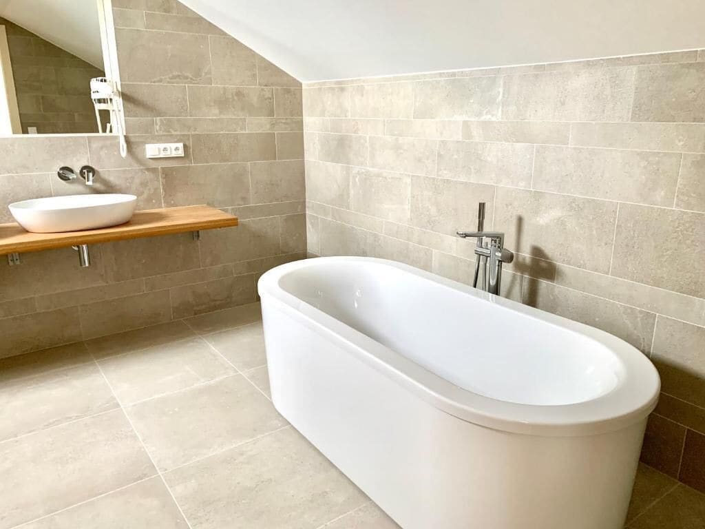 A modern bathroom with a freestanding bathtub, a wooden vanity with a white sink, and a large mirror.