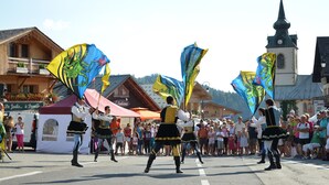 Ein Straßenumzug mit Darstellern in traditioneller Tracht und Fahnen.