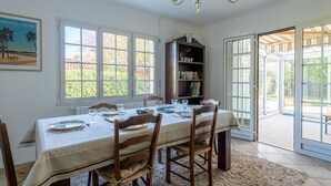 A dining room with a table set for four, a bookshelf, and a chandelier. - Cozy Family Home in Parentis-en-Born: 3BR, WiFi, Large Garden, Near Beach & Lake (Parentis-en-Born)
