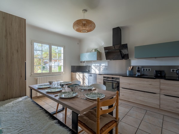 Una cocina moderna con una mesa de comedor para cuatro personas, horno empotrado y un amplio ventanal que proporciona luz natural.