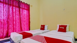 A hotel room with two single beds, each with a red and white bedspread and pillows labeled "OYO". The room has a yellow wall and a window with red curtains. - Hotel O P3 Guest House (Cileunyi)