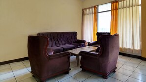 A room with a dark brown sofa, two matching armchairs, and a wooden coffee table. - Hotel O P3 Guest House (Cileunyi)