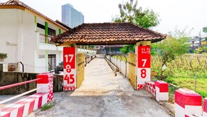 A gated entrance with numbered gates, a tiled roof, and a pathway leading into a building. - Hotel O P3 Guest House (Cileunyi)