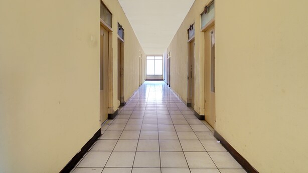 A long, narrow hallway with tiled floors and cream-colored walls, leading to a bright window at the end. - Hotel O P3 Guest House (Cileunyi)