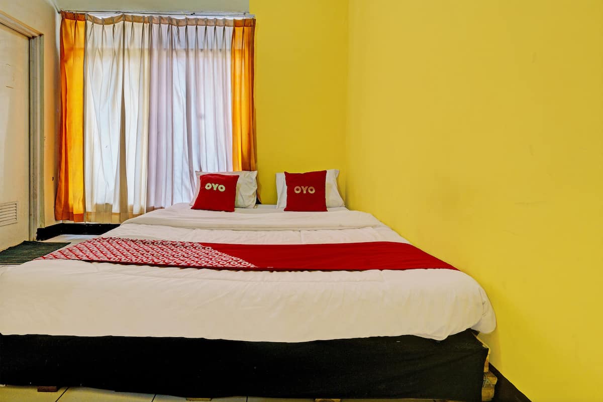 A bed with white and red bedding, two red pillows with "OYO" text, and a red and white patterned throw.