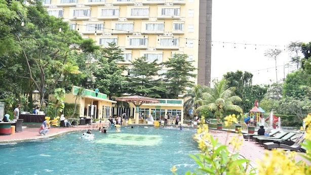 A swimming pool surrounded by greenery and a building with multiple balconies. -  LORIN SYARIAH HOTEL SENTUL (Bogor)