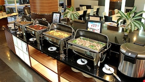 A buffet setup with multiple food stations, a coffee machine, and seating areas in a modern dining space. -  LORIN SYARIAH HOTEL SENTUL (Bogor)