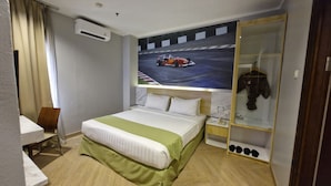 A hotel room with a bed, a desk, a chair, a wardrobe, and a racing car poster on the wall. -  LORIN SYARIAH HOTEL SENTUL (Bogor)