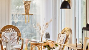 Un coin repas accueillant avec des chaises en osier, une table ronde et un luminaire suspendu en macramé.