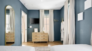 A bedroom with two beds, a dresser, a TV, and a mirror. - Occasionally Luxe | Girls Trip Dream Home (Charleston)