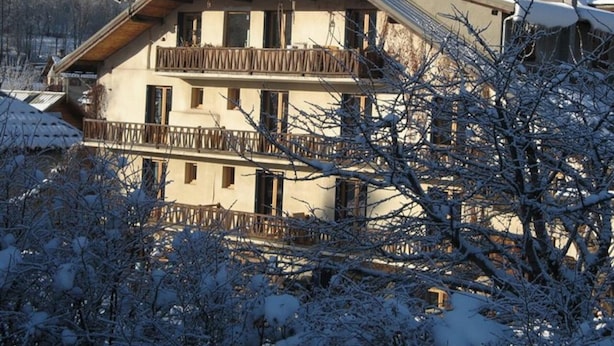 A multi-story building with balconies, surrounded by snow-covered trees. - Cozy 1BR Apartment, Balcony, Pool, Close to Serre Chevalier Slopes, Free Wi-Fi & Parking (Saint-Chaffrey)