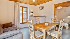 A cozy room with a wooden ceiling, a dining table with chairs, a sofa, and a window with curtains. - Cozy 1BR Apartment, Balcony, Pool, Close to Serre Chevalier Slopes, Free Wi-Fi & Parking (Saint-Chaffrey)