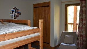 Un dormitorio con una cama de madera, una silla pequeña, un armario de madera y una pared decorada con fotografías.