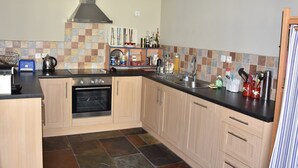Una cocina moderna con armarios de madera, horno integrado, pileta de acero inoxidable y un respuesto con azulejos.