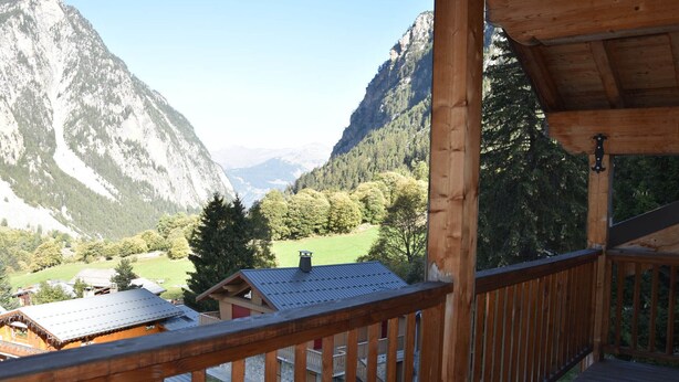 Un balcón de madera con vistas a un paisaje montañoso.