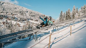 Sneeuwlandschap met bergen, een skilift en houten chalets.