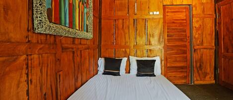 Una habitación de madera con una cama, aire acondicionado instalado en la pared y una puerta.